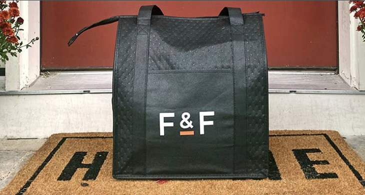 Feast and Fettle delivery black bag on welcome mat on front door, door is red.